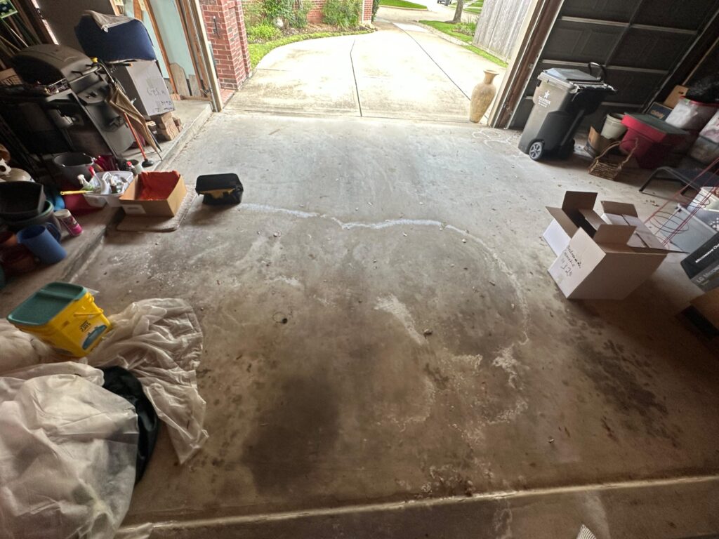 Stained, patched concrete garage floor before epoxy