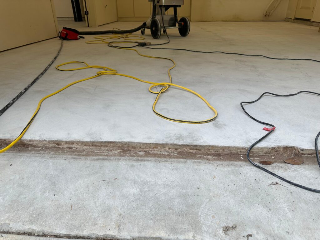 Diamond ground concrete garage slab with grinder and dust vacuum hose